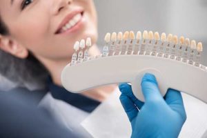 a woman holds a sample of dental veneers